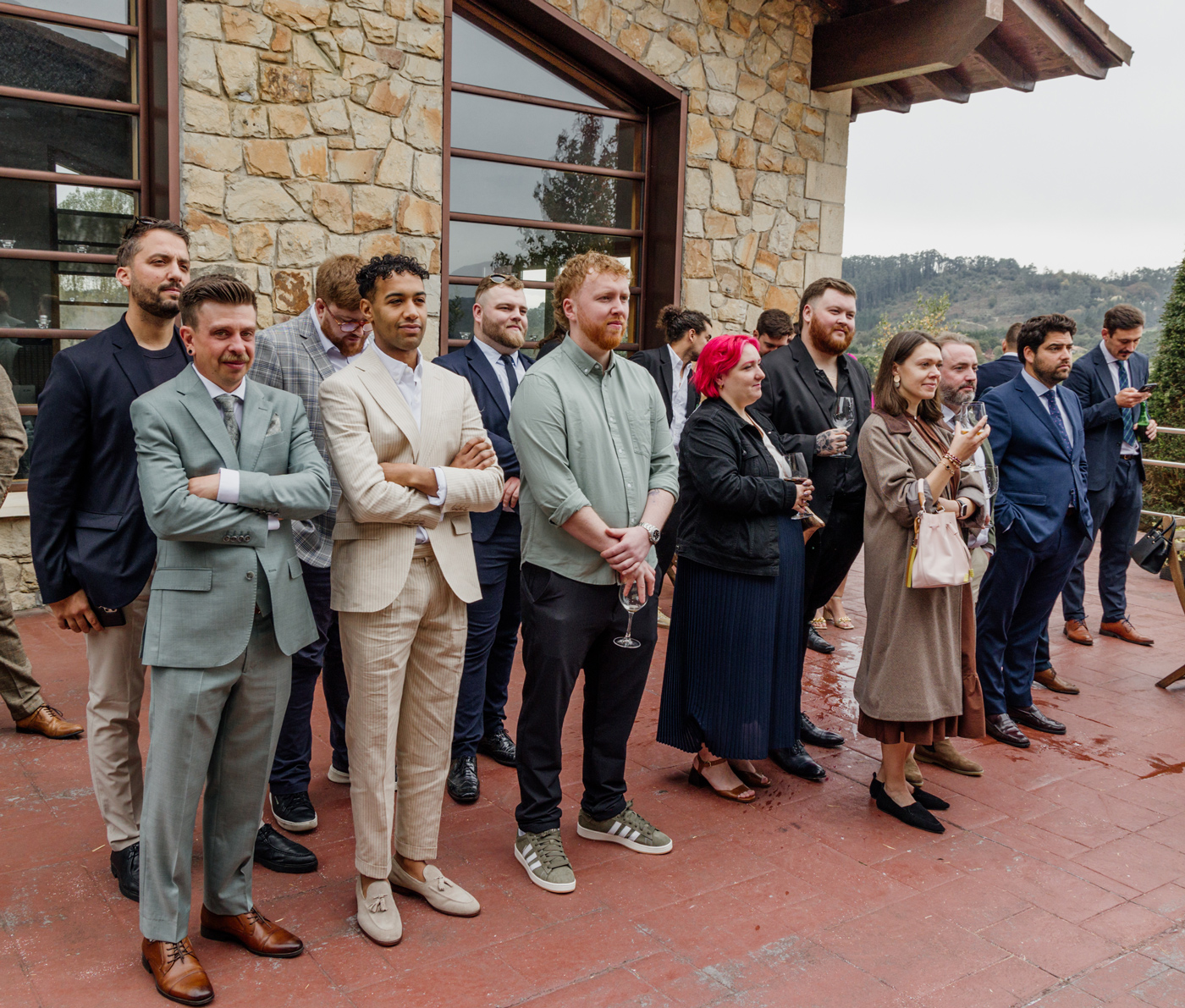 Grupo de invitados observando la ceremonia en una boda al aire libre junto a un caserio, fotografía documental realizada por un fotógrafo de bodas en Bizkaia.
