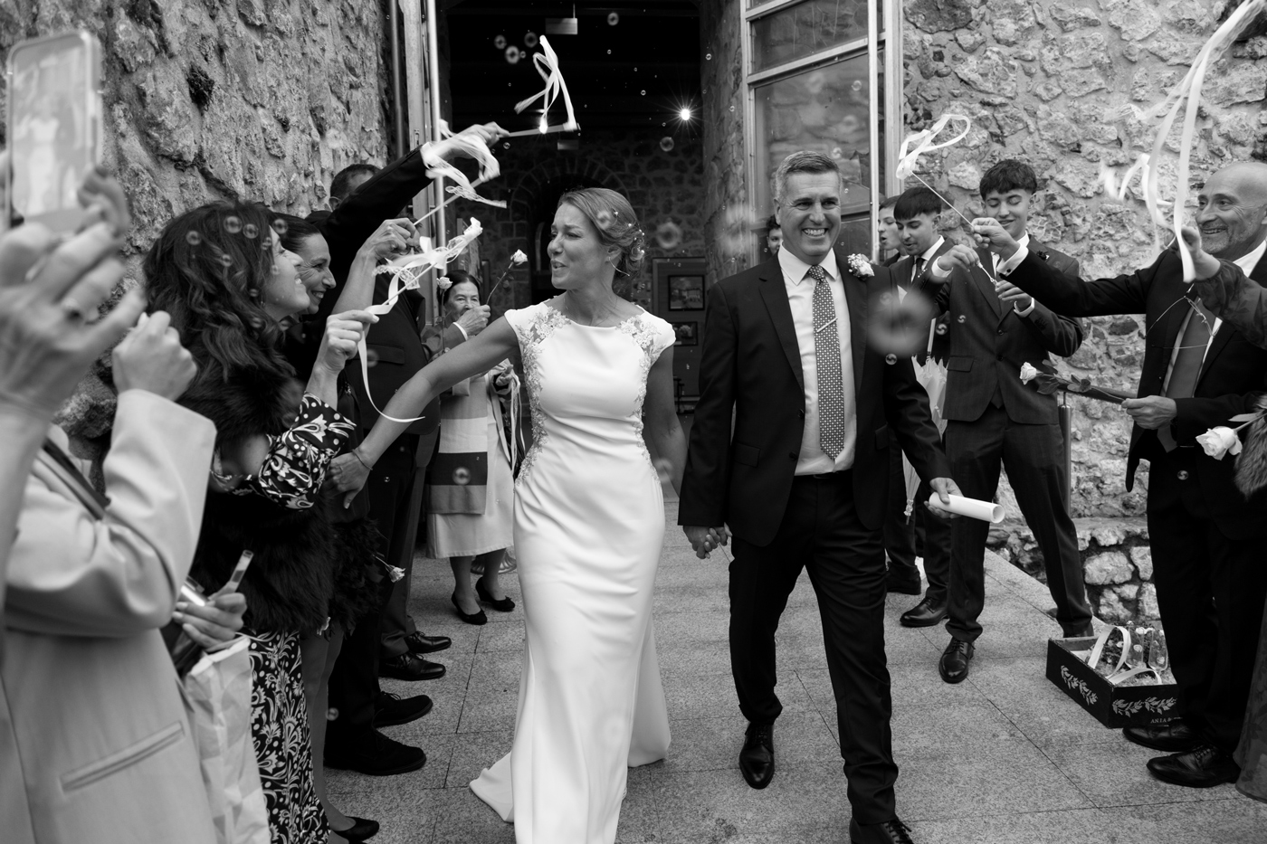 Fotógrafo de bodas en Cantabria captando la celebración de la salida de los novios, rodeados de invitados lanzando cintas y aplaudiendo.