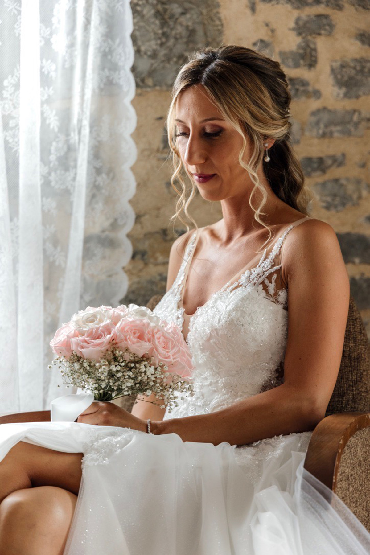 Novia sentada junto a una ventana sosteniendo su ramo en un momento previo a la ceremonia, fotografiada por un fotógrafo de bodas en Bilbao.