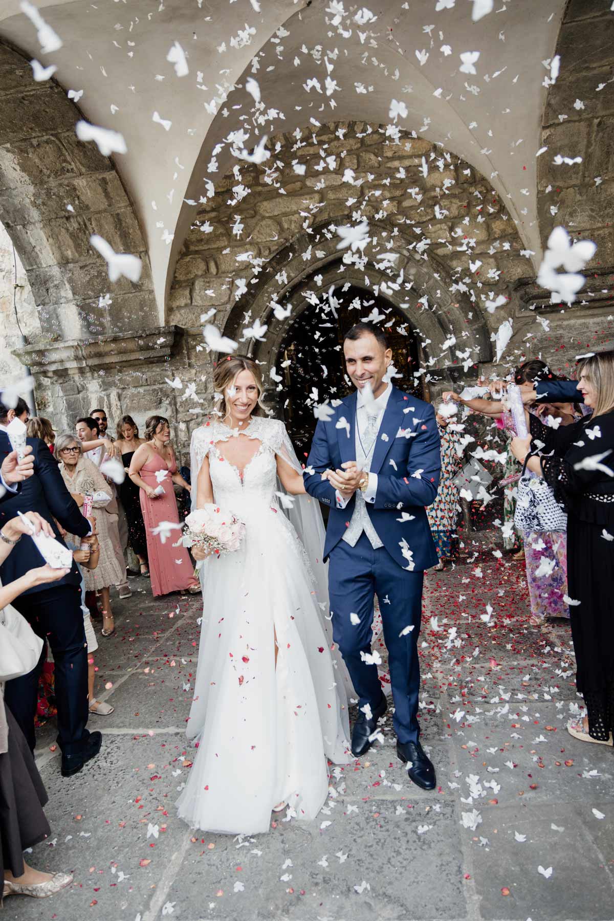 Recién casados saliendo de la iglesia entre una lluvia de pétalos y confeti, fotografiados por un fotógrafo de bodas en Bilbao.