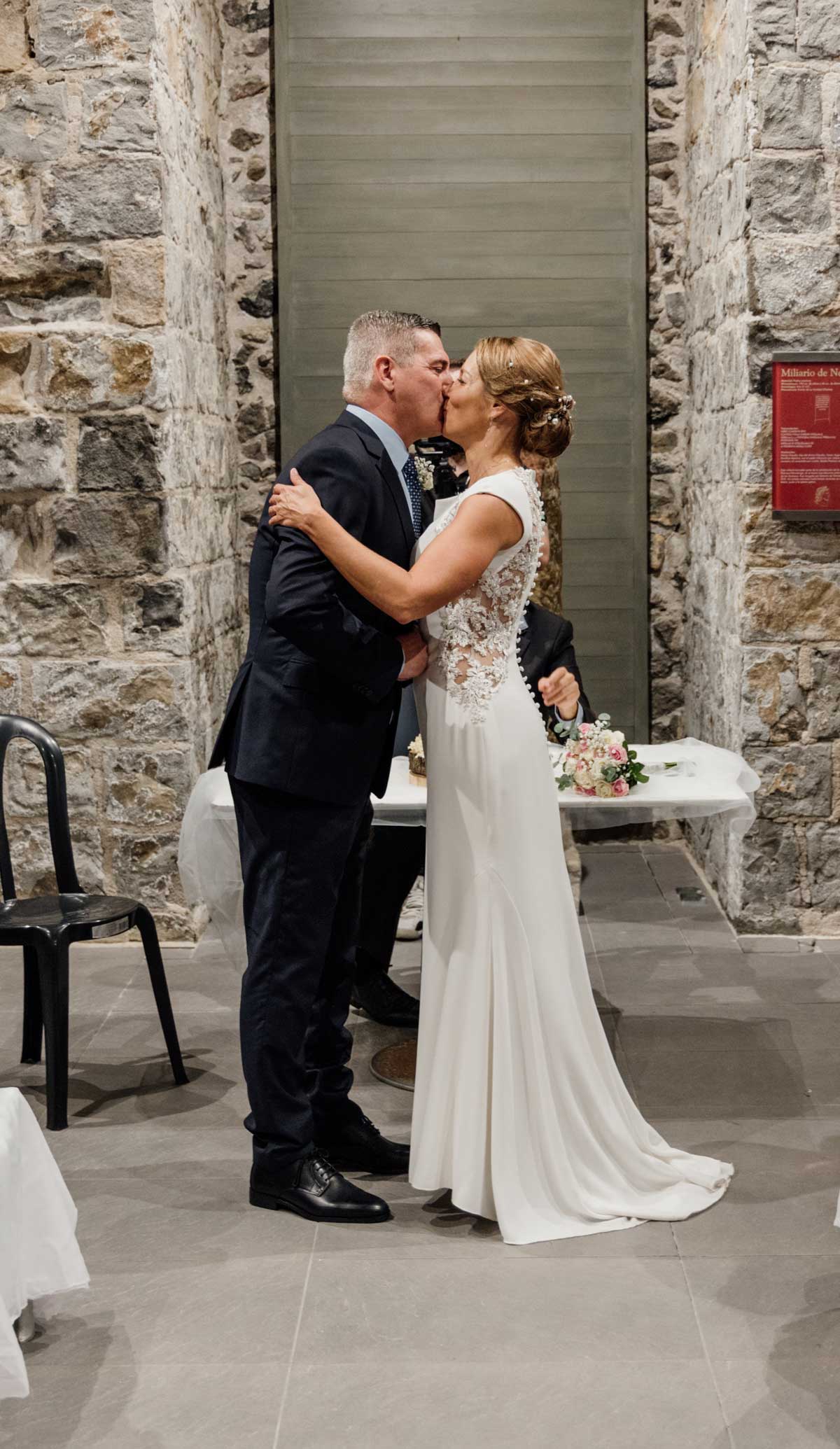 Pareja de recién casados besándose durante la ceremonia en un espacio interior de piedra en Cantabria