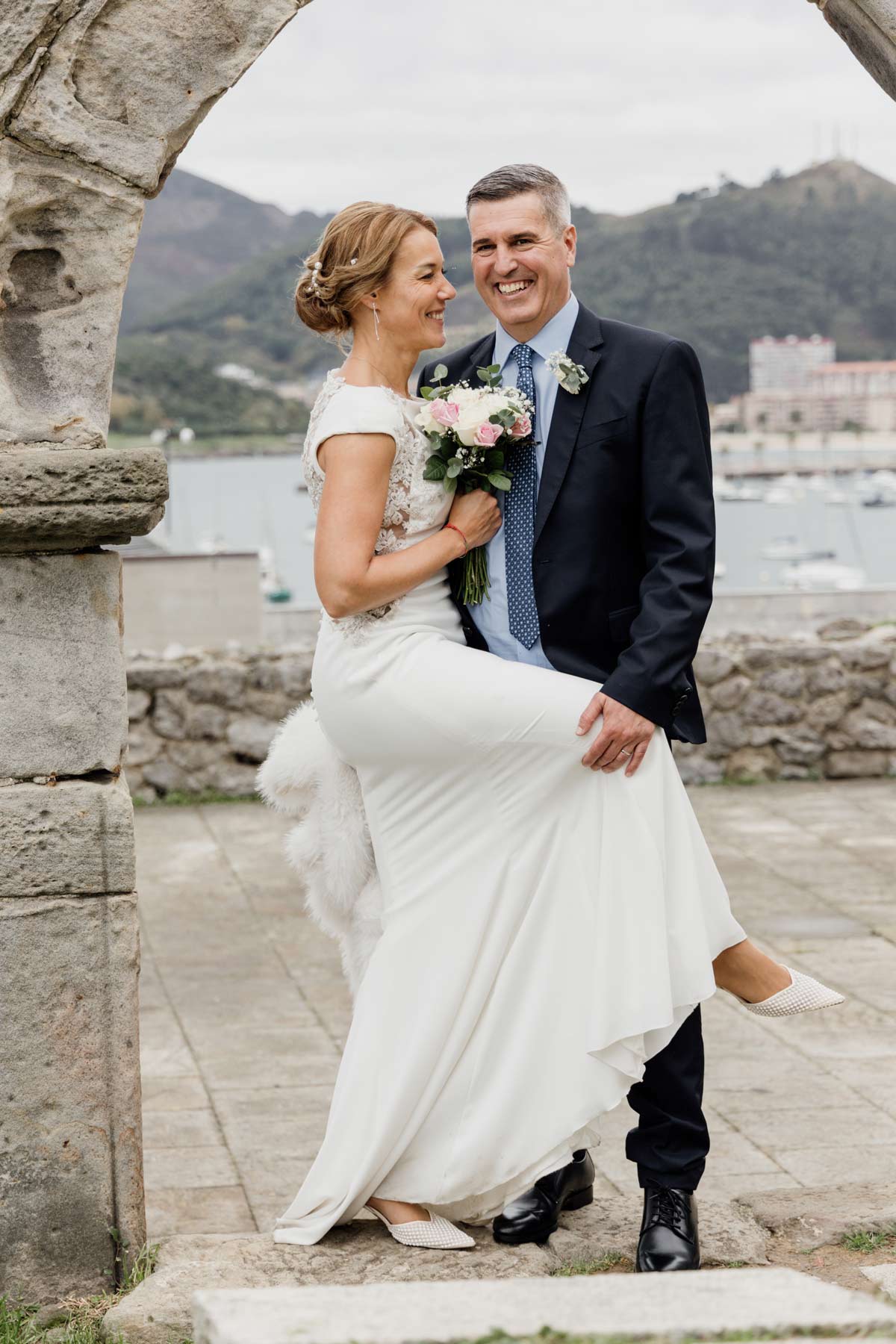 Pareja de recién casados posando sonrientes en un entorno costero en Cantabria durante su reportaje de boda