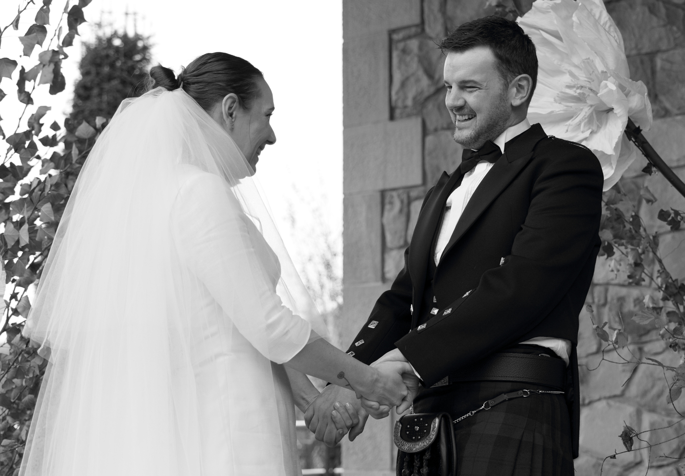 Pareja de recién casados tomándose de las manos y sonriendo durante la ceremonia, fotografía en blanco y negro realizada por un fotógrafo de bodas en Bizkaia.