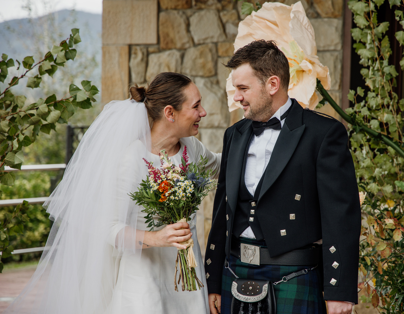 Pareja de recién casados sonriendo y mirándose con complicidad al aire libre, fotografía de boda realizada por un fotógrafo de bodas en Bizkaia.