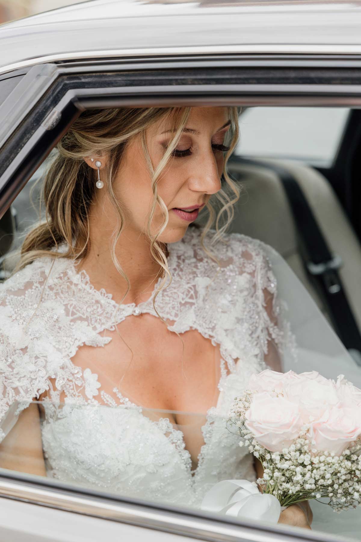 Novia acomodándose dentro del coche mientras sostiene su ramo, fotografiada por un fotógrafo de bodas en Bilbao.