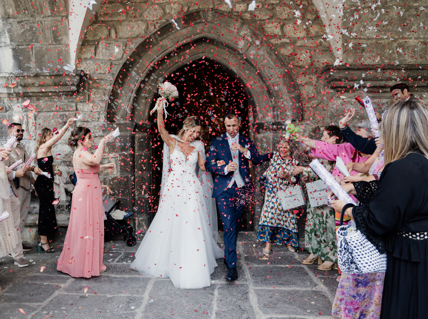 Salida de los recién casados bajo una lluvia de confeti a las puertas de la iglesia, fotografiada por un fotógrafo de bodas en Bilbao.