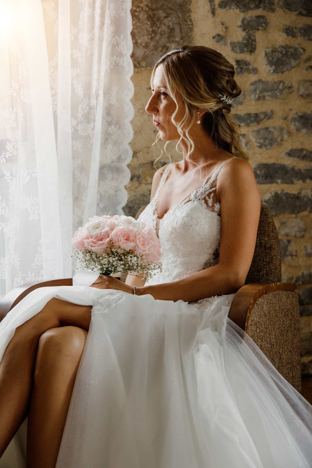 Novia sentada junto a una ventana sosteniendo su ramo antes de la ceremonia, fotografiada por un fotógrafo de bodas en Bilbao.