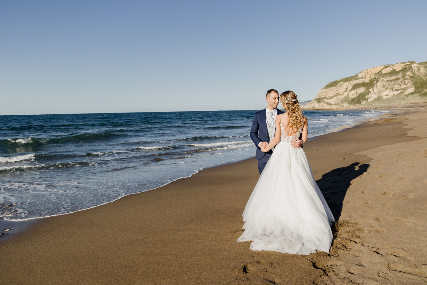 Pareja de novios posando en la orilla de la playa durante su postboda - Fotógrafo de bodas en Bizkaia.