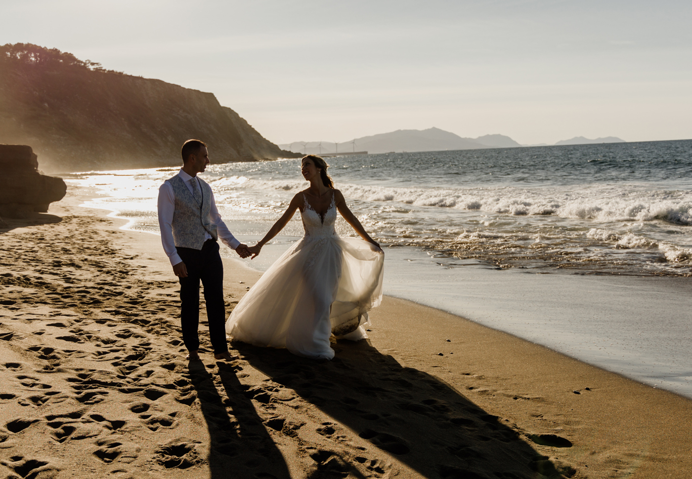 Pareja de novios caminando por la playa al atardecer durante su postboda — Fotógrafo de bodas en Bizkaia.