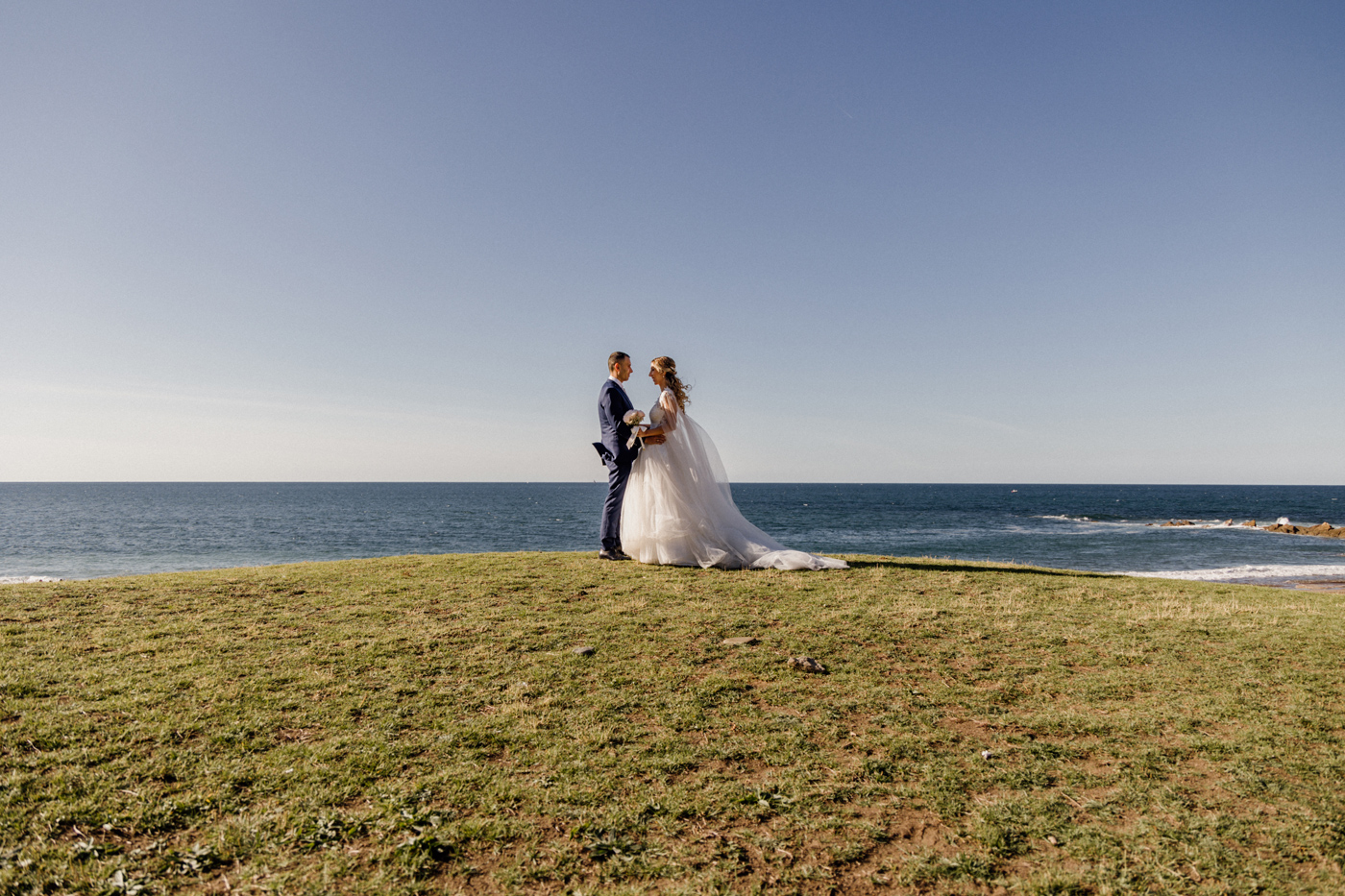 Pareja de novios posando frente al mar en un acantilado durante su postboda — Fotógrafo de bodas en Bizkaia.